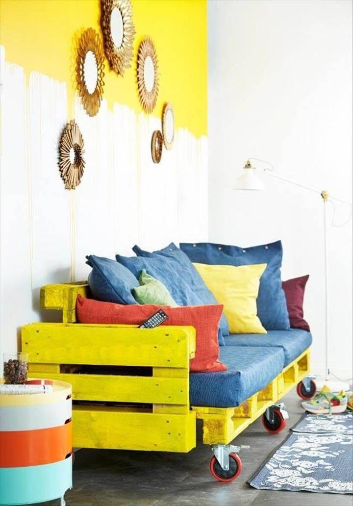 yellow painted pallet rolling sofa with blue cushion